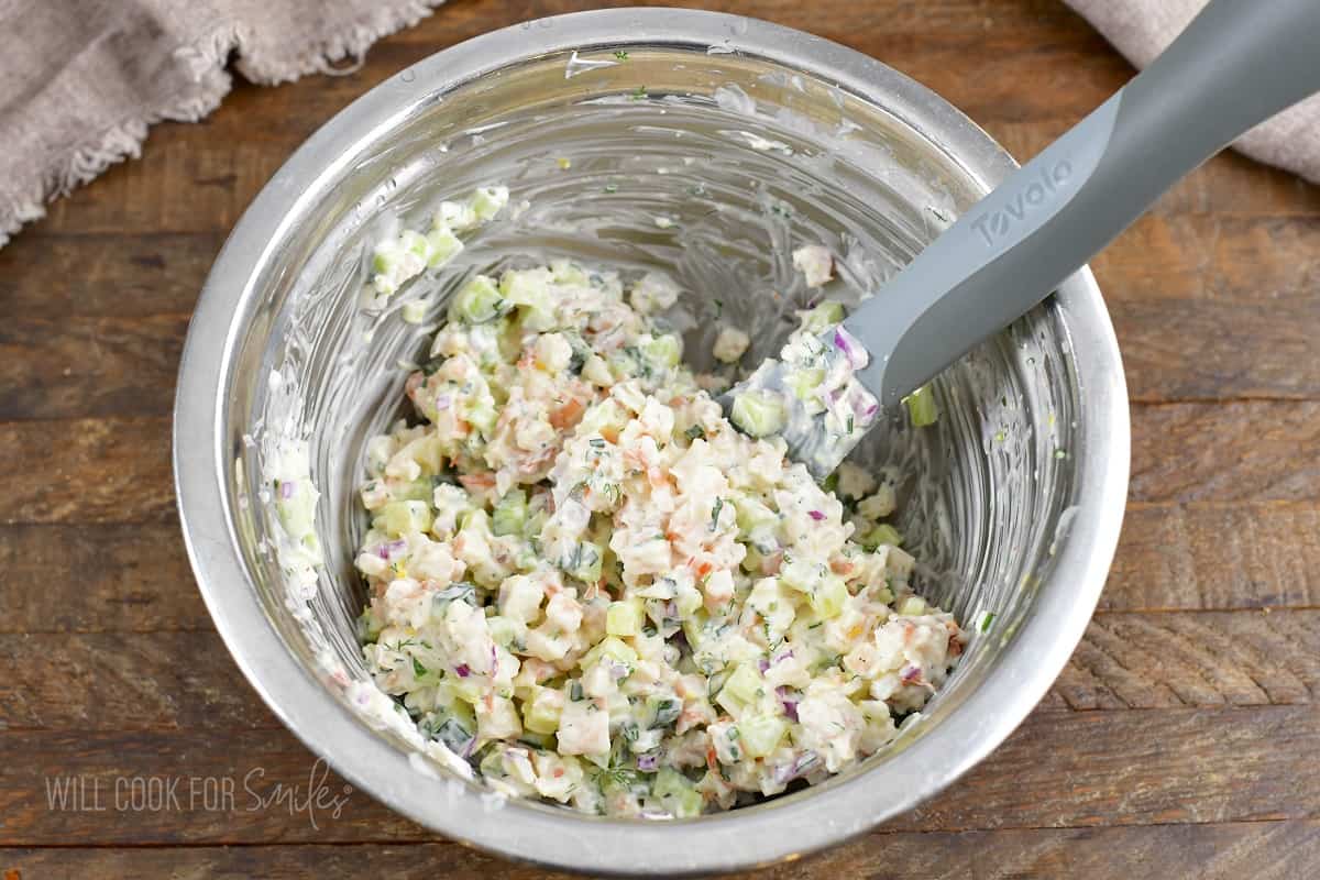 mixing shrimp salad in a metal bowl.