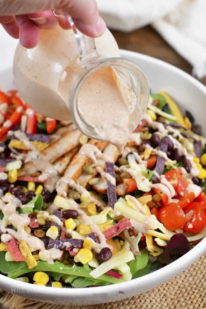 adding creamy salsa dressing over the salad.