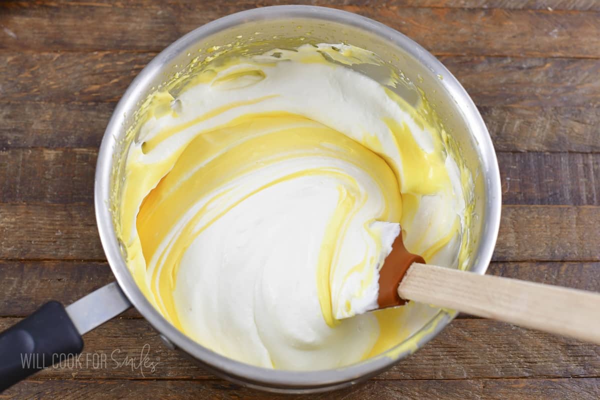 folding whipped cream into egg mixture in a pot.