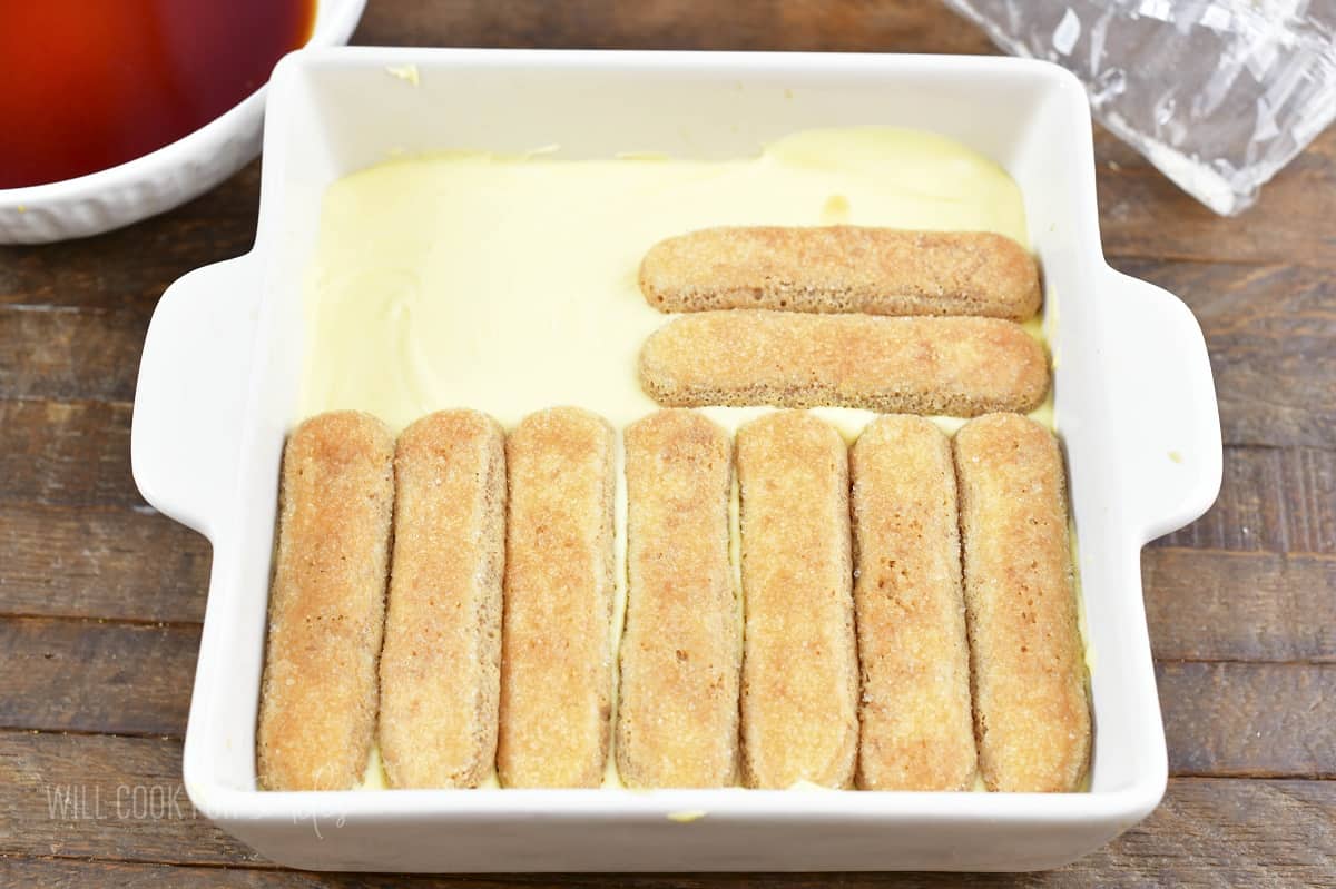 layering more lady fingers on top of mascarpone cream.