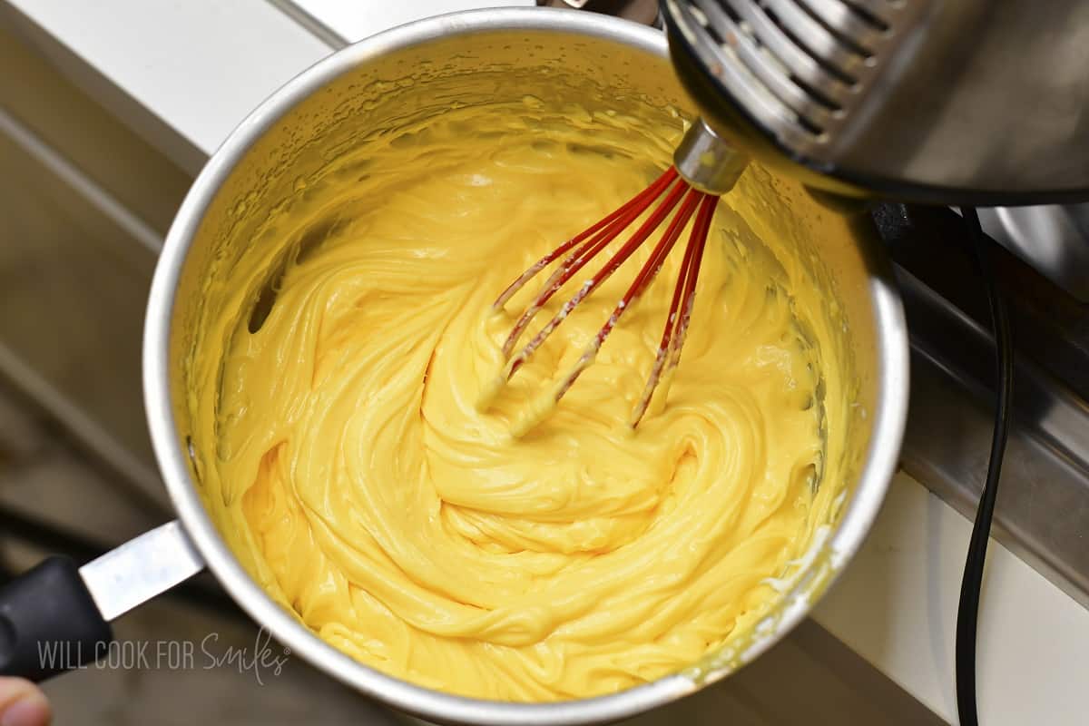 whisking mascarpone into egg whites in a pot.
