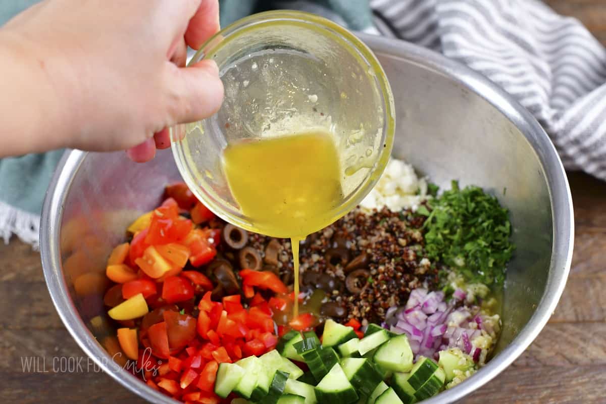 adding Greek dressing to the quinoa salad ingredients.