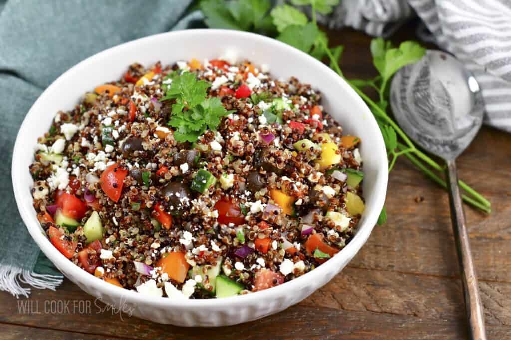 Mediterranean quinoa salad in a bowl with spoon next to it.