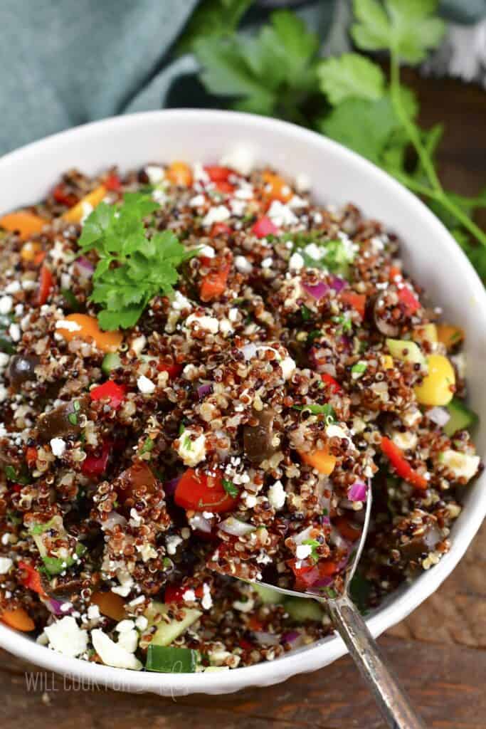 starting to scoop out some quinoa salad out of the bowl.