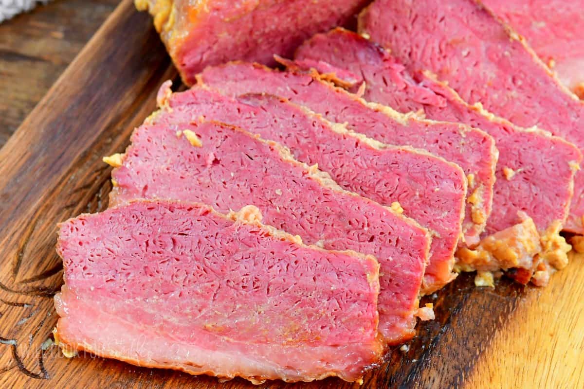 closeup of sliced corned beef brisket on wooden plate.