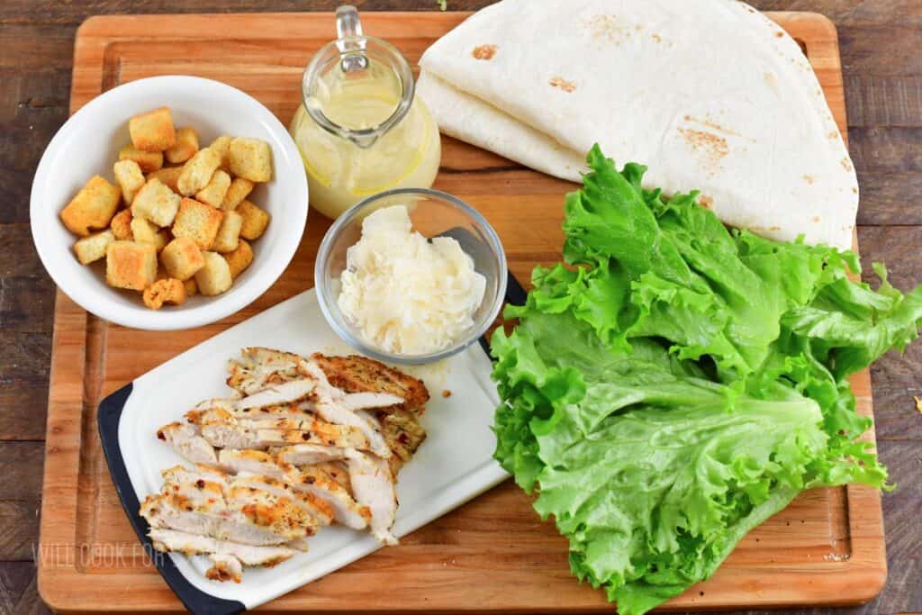 ingredients to make chicken caesar wraps on cutting board.