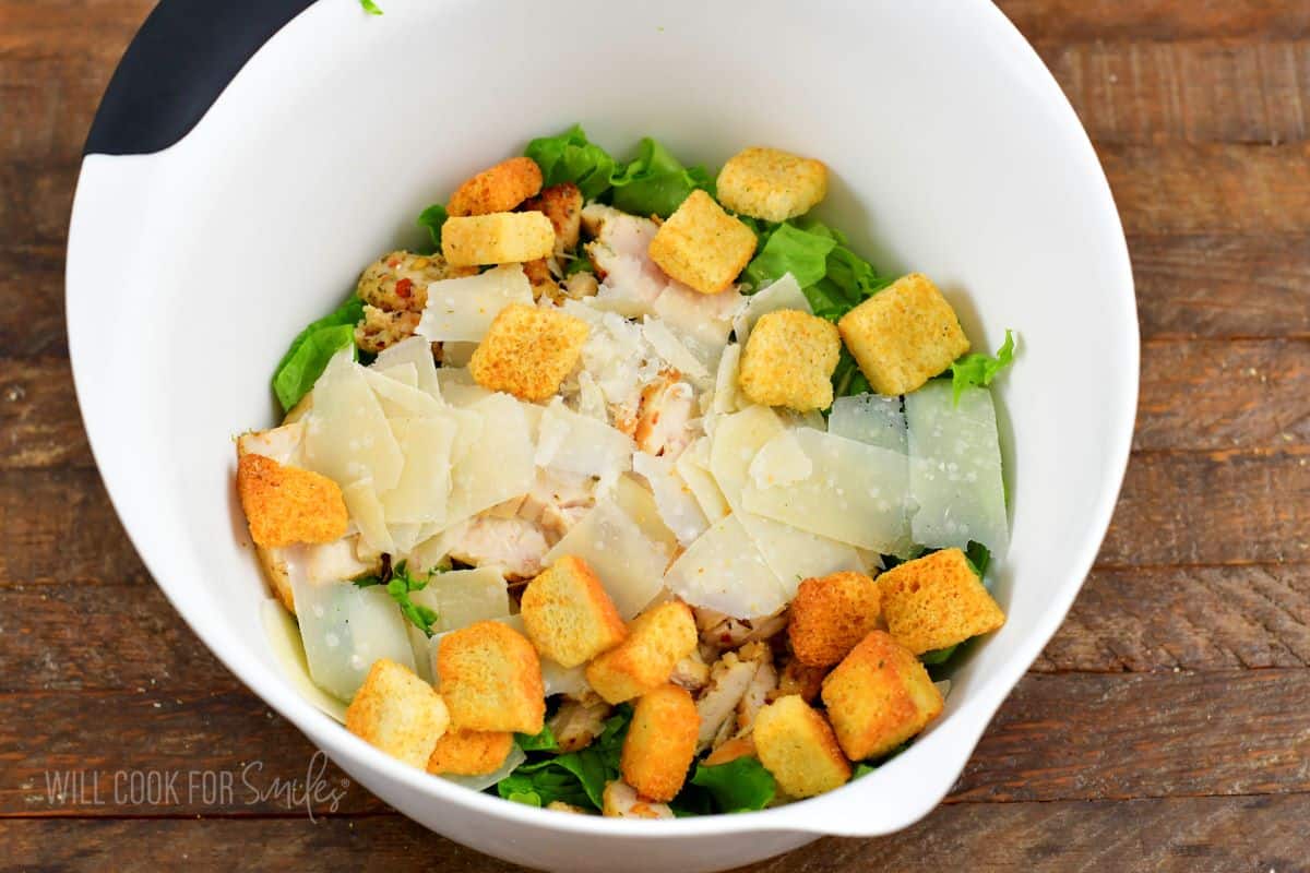 chicken caesar salad ingredients in a mixing bowl.