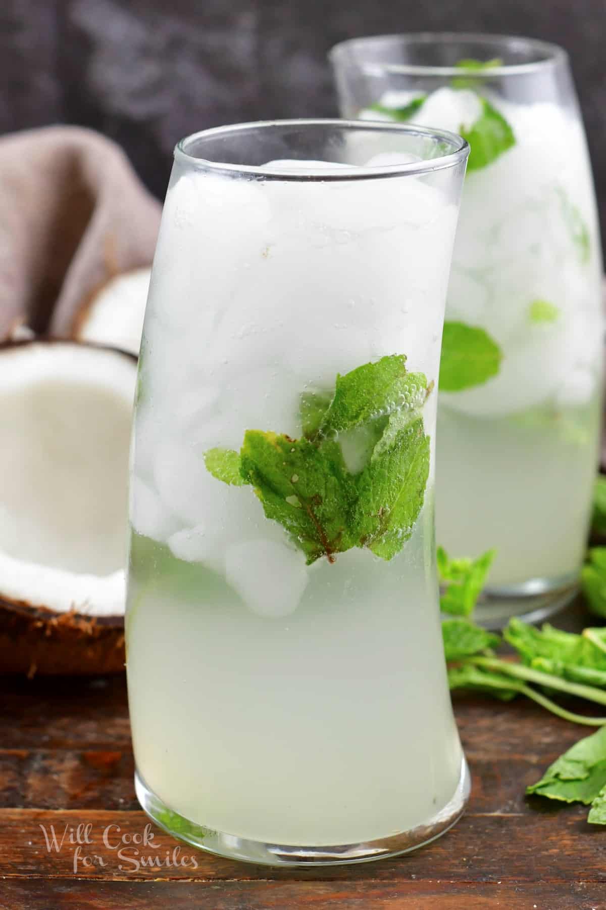 two tall glassed filled with a white coconut mojito and mint leaves.