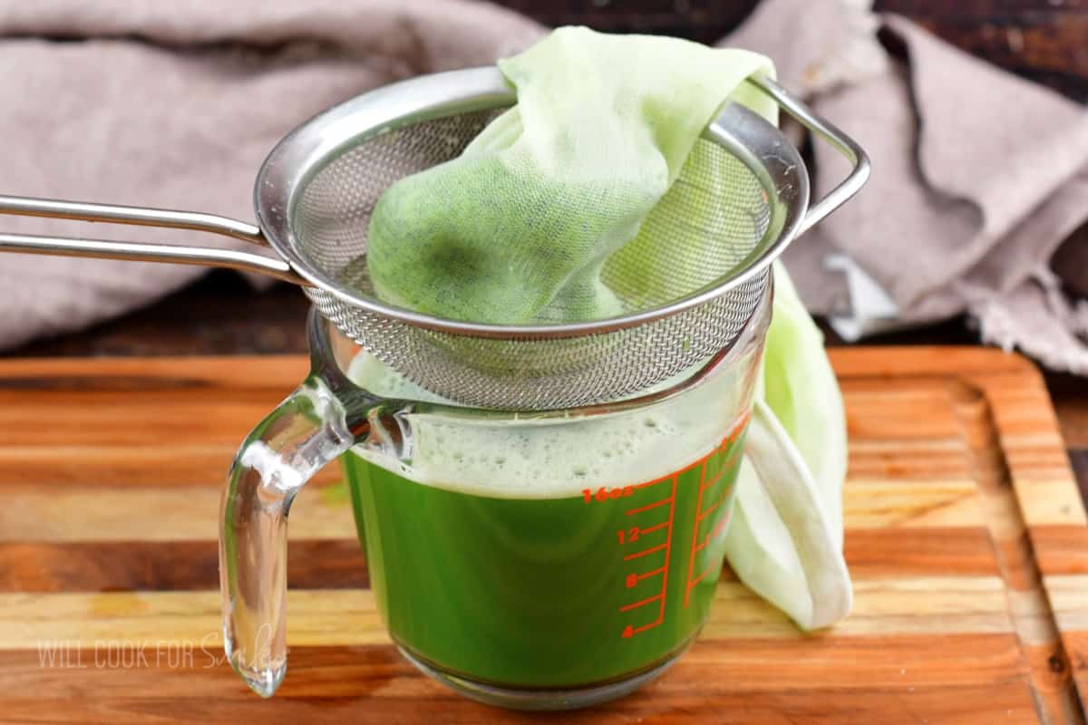 cucumber juice in a measuring cup with cucumber pulp in a bag.