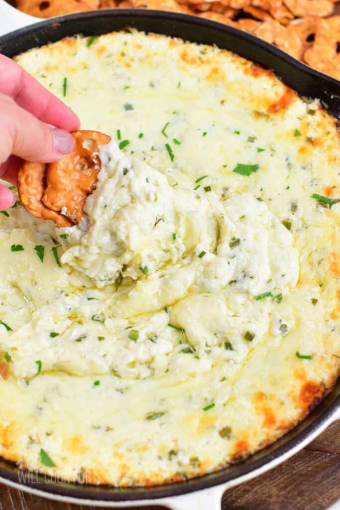 scooping gooey baked cheese dip from the skillet.