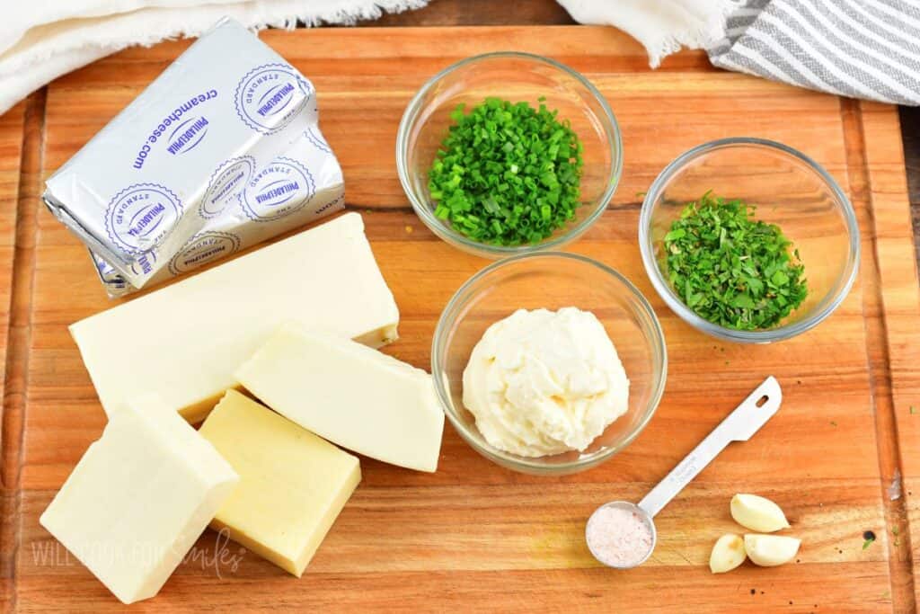 ingredients for four cheese dip on cutting board.