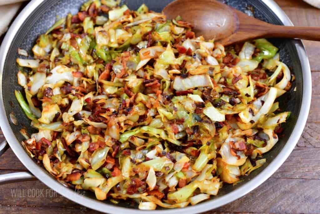closeup of fried cabbage in a cooking pan with spoon.