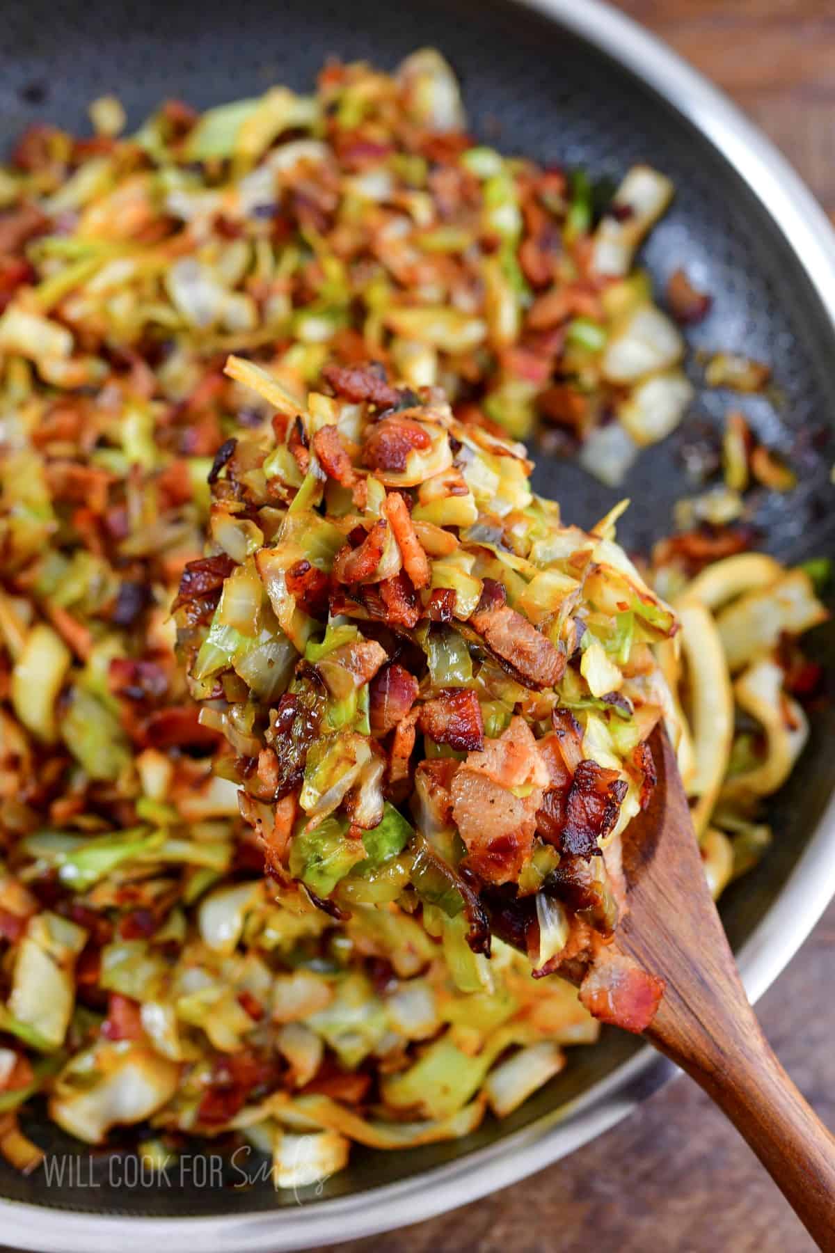 fried cabbage on a wooden spoon above the pan.