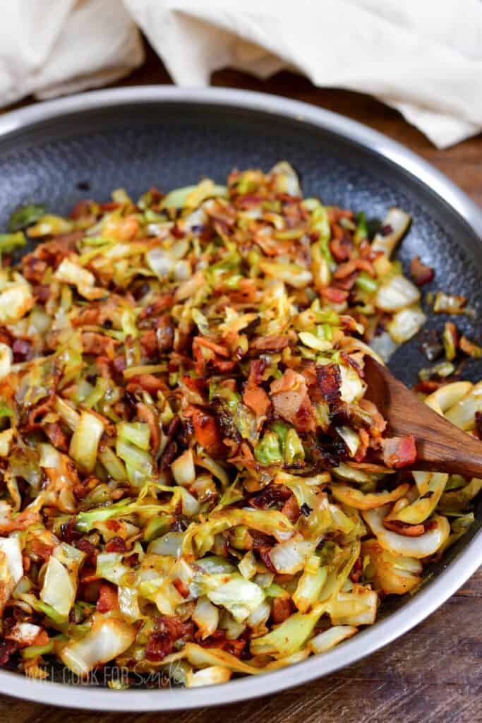 fried cabbage in a cooking pan with a wooden spoon.