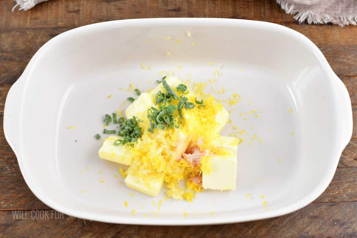 butter, garlic, sage, and lemon zest in a white baking dish.