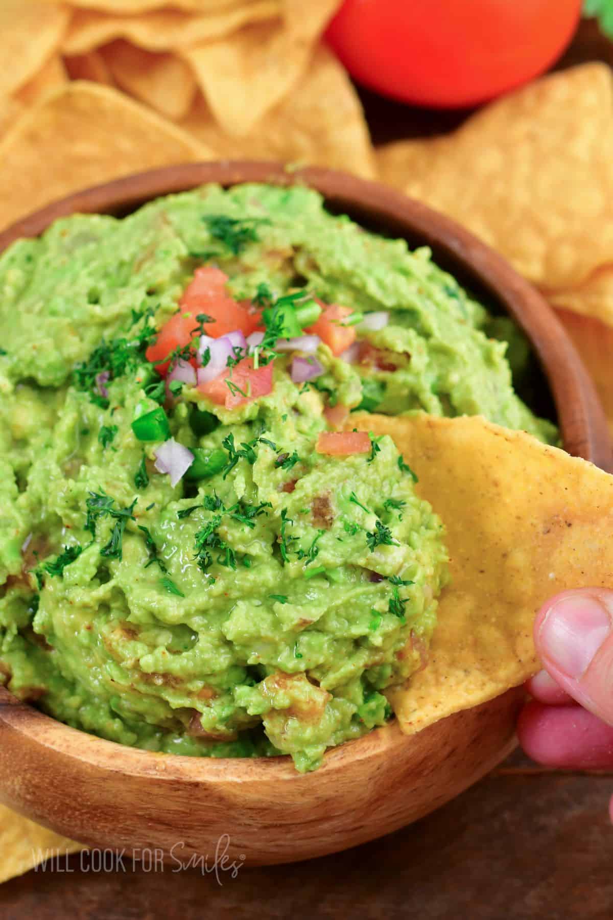 scooping out some guacamole with a tortilla chip.