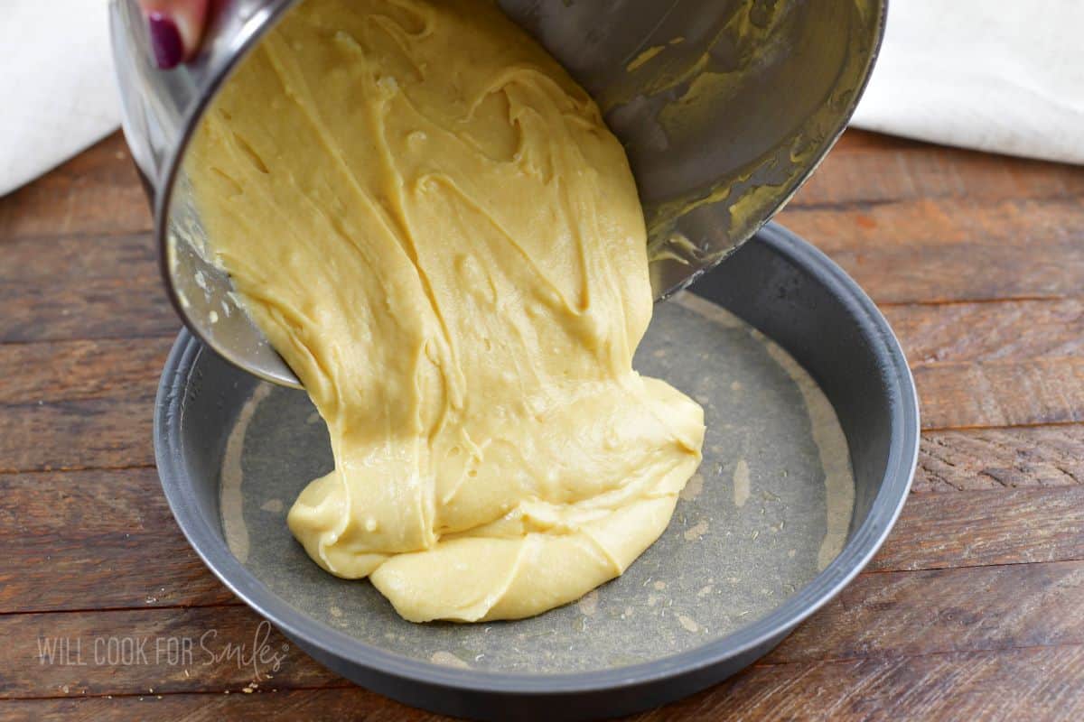 pouring cake batter into the cake pan lined with parchment.