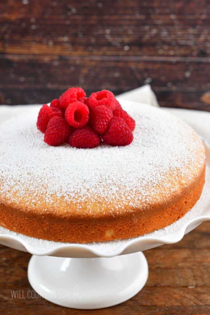 Irish tea cake on the white cake stand with raspberries.