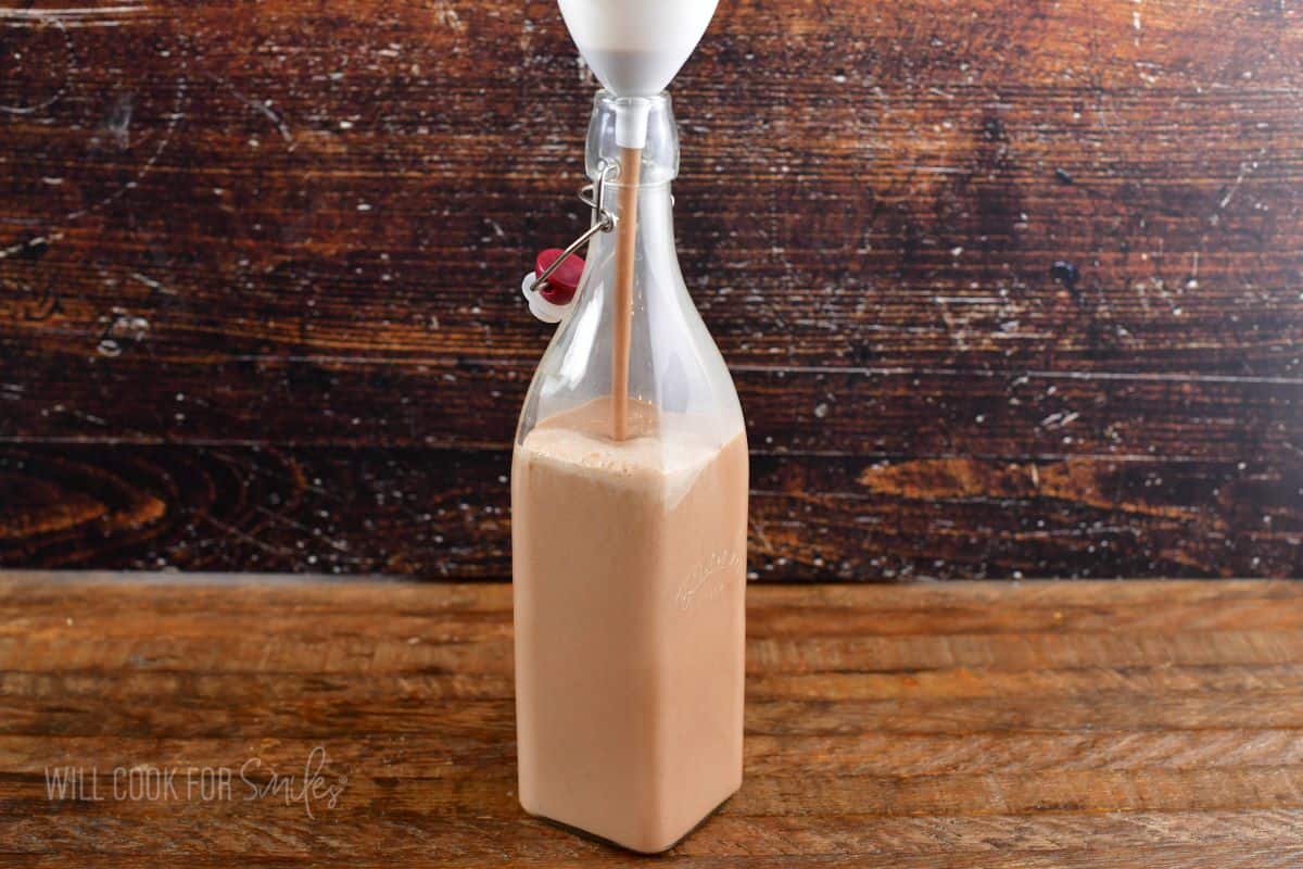 pouring Irish cream into a tall bottle.