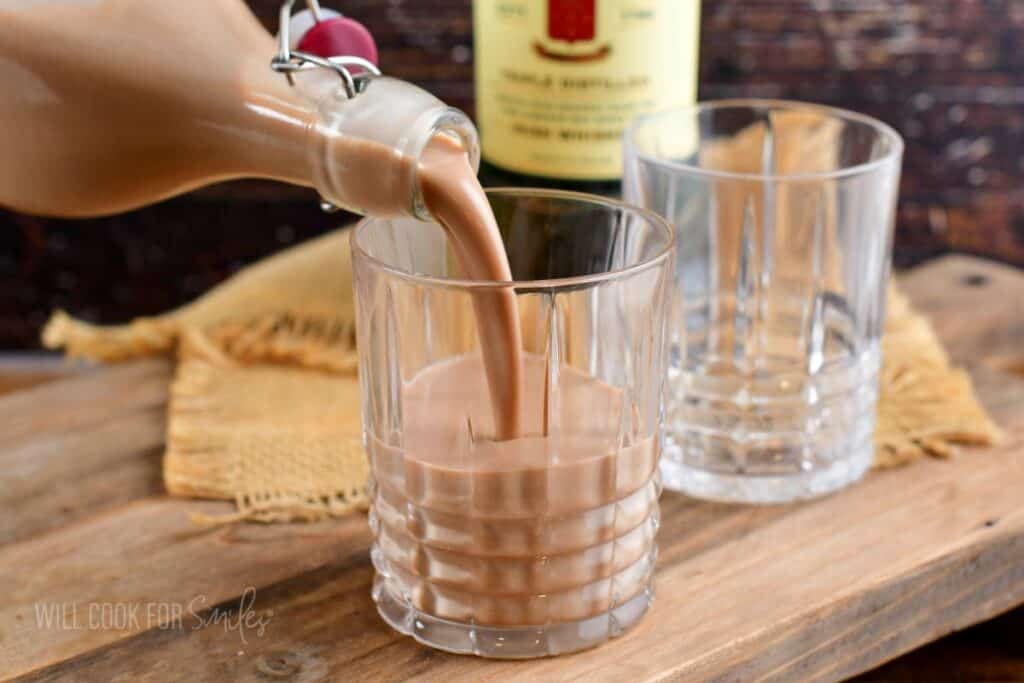 Pouring Irish cream into the glass from a bottle.