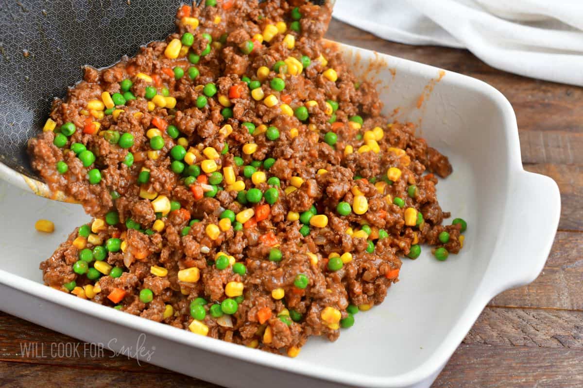 adding cooked beef and vegetables into the casserole dish.