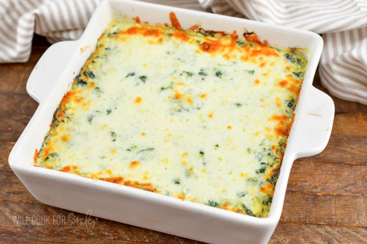baked spinach artichoke dip in a white baking dish.