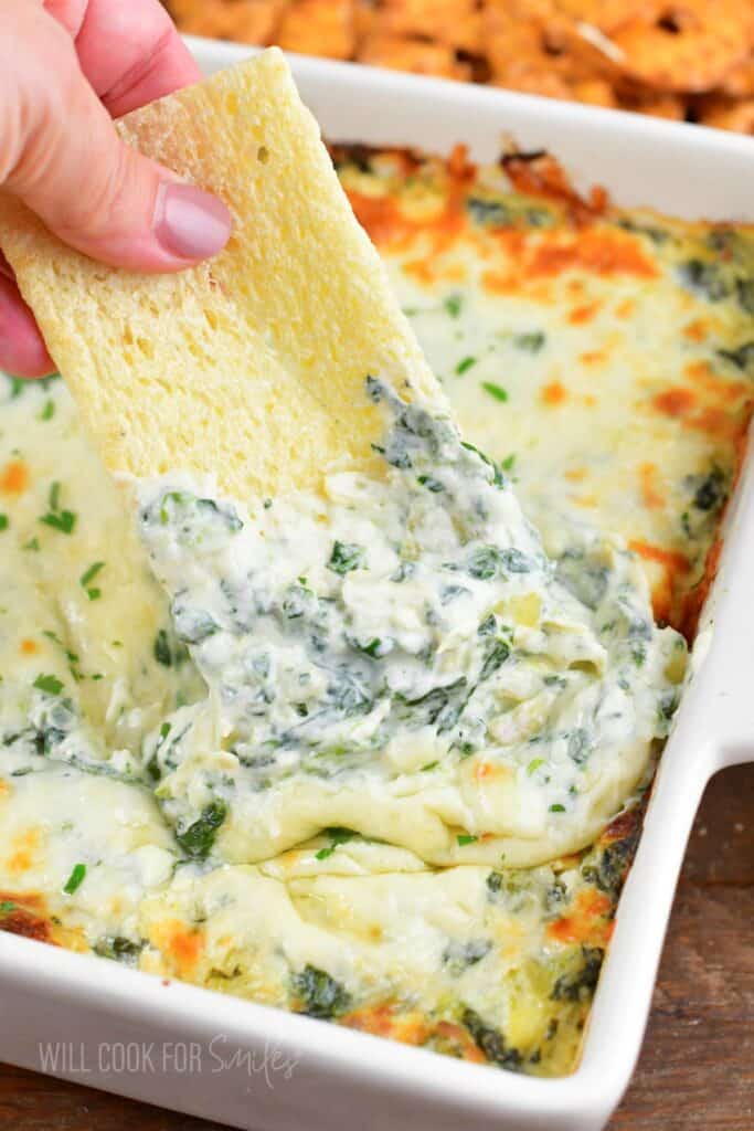 scooping some spinach dip with a large cracker.