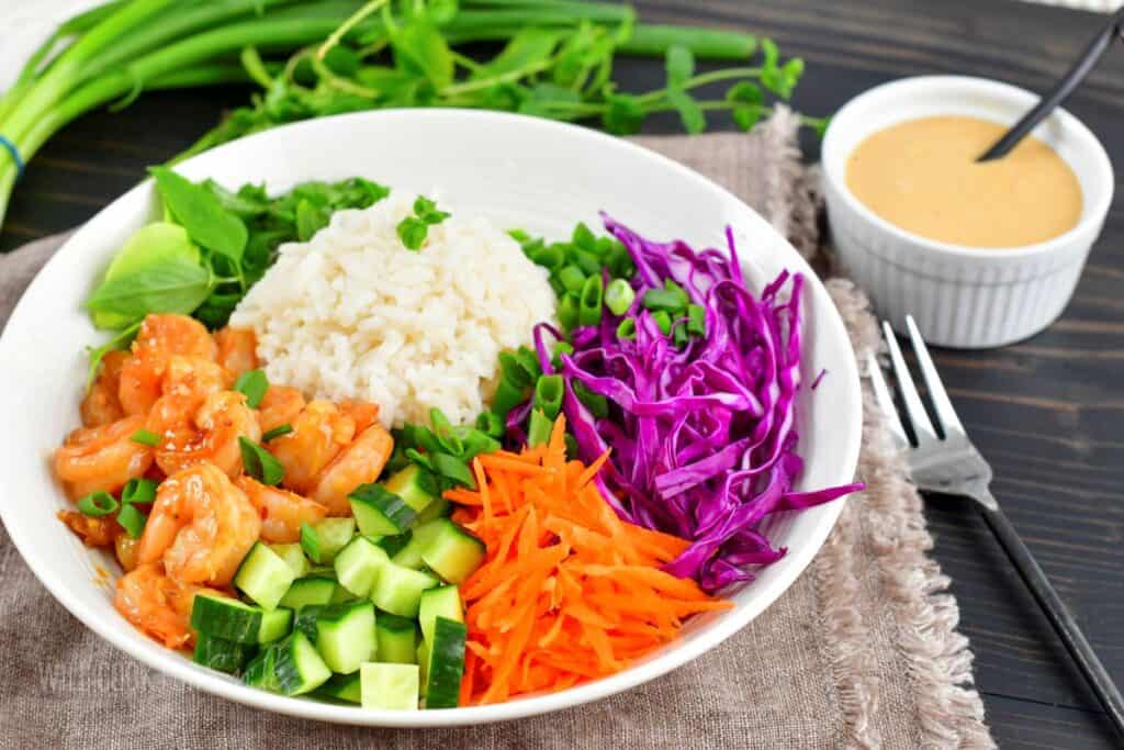 side view of veggies, shrimp and rice in a bowl.