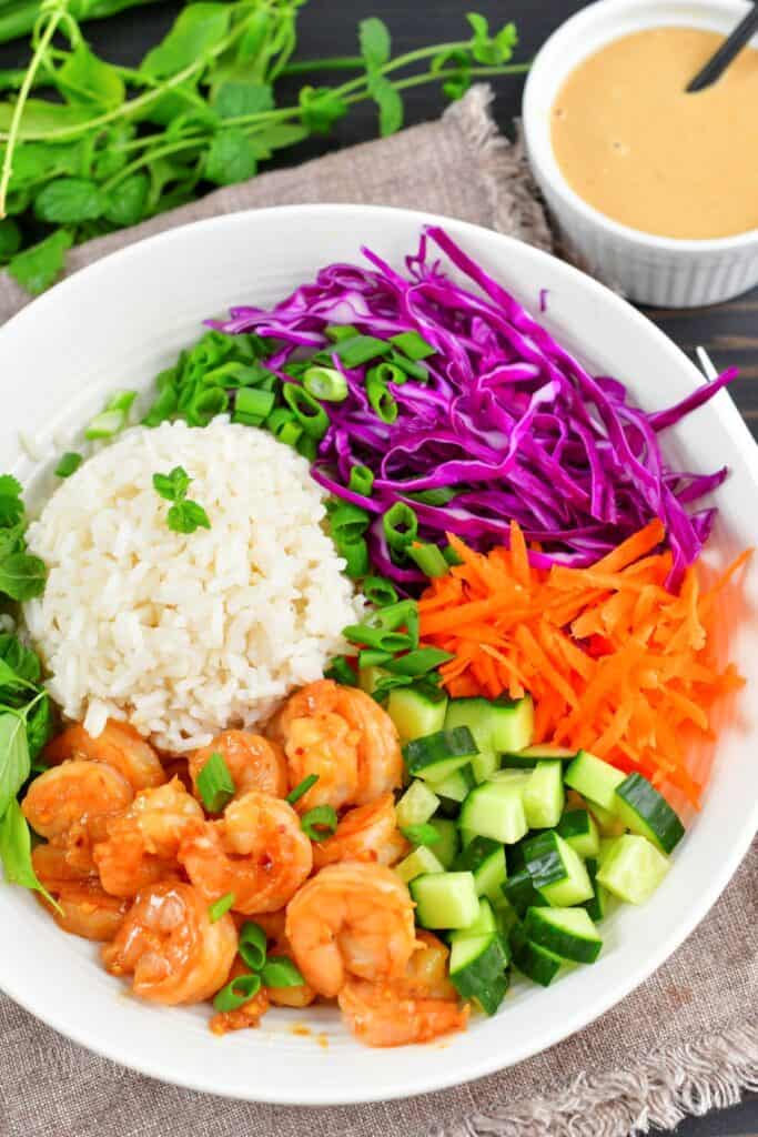 top view of bowl with shrimp, rice, cabbage, carrots, cucumbers.