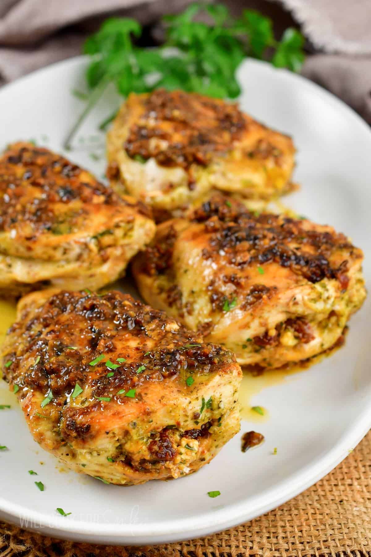 four pesto tomato stuffed chicken breasts on a platter.