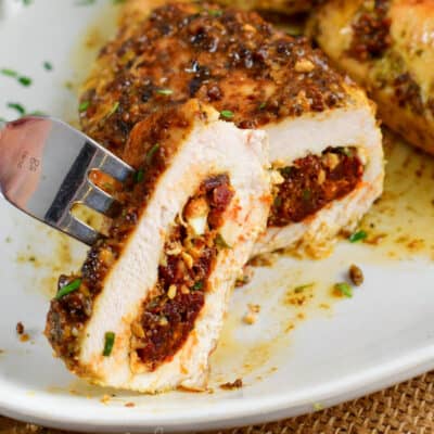 closeup of cut chicken breast stuffed with tomatoes and feta.