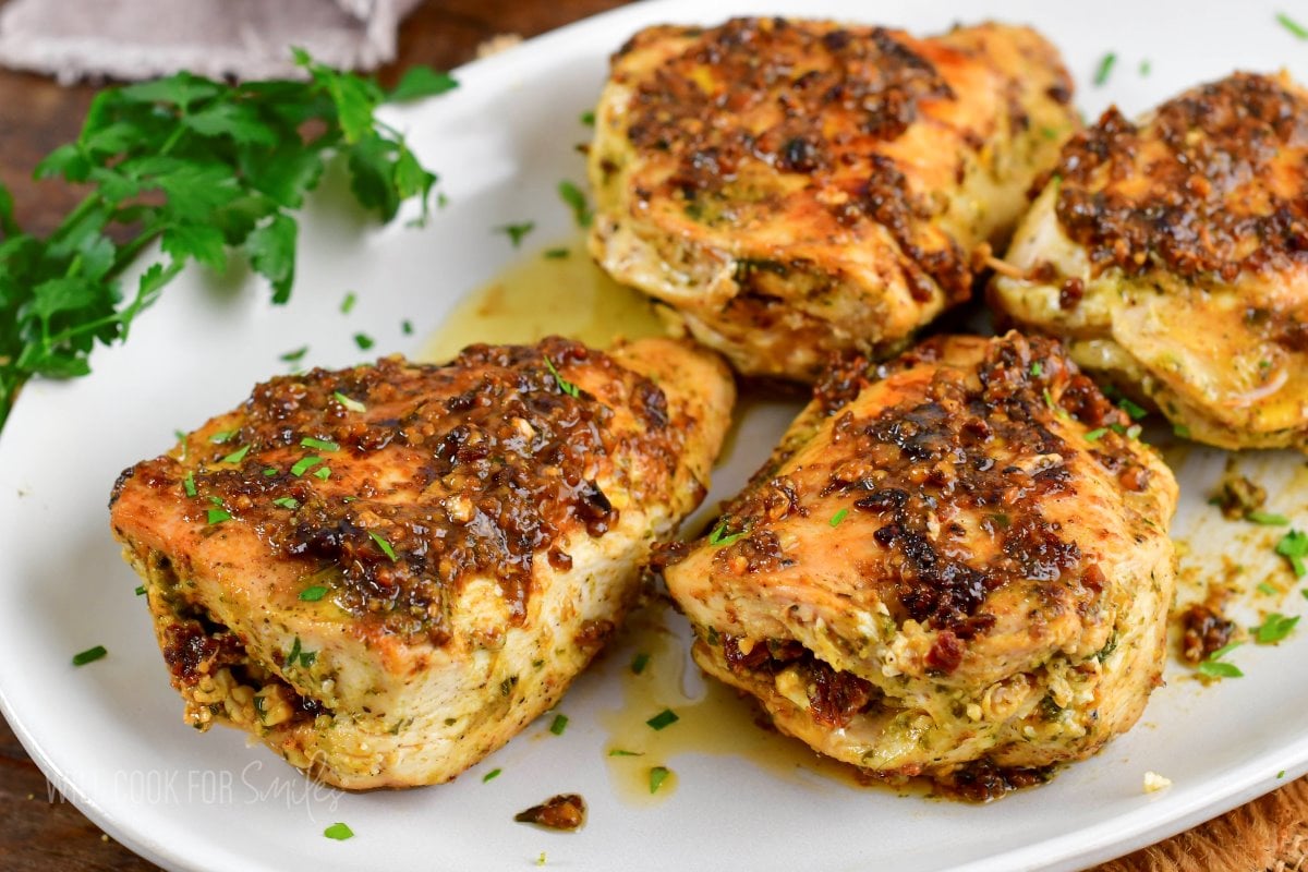 closeup of four pesto stuffed chicken breasts on a plate.