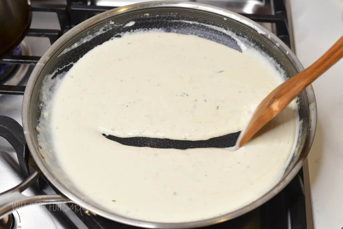 stirring parmesan cream sauce in the pan.