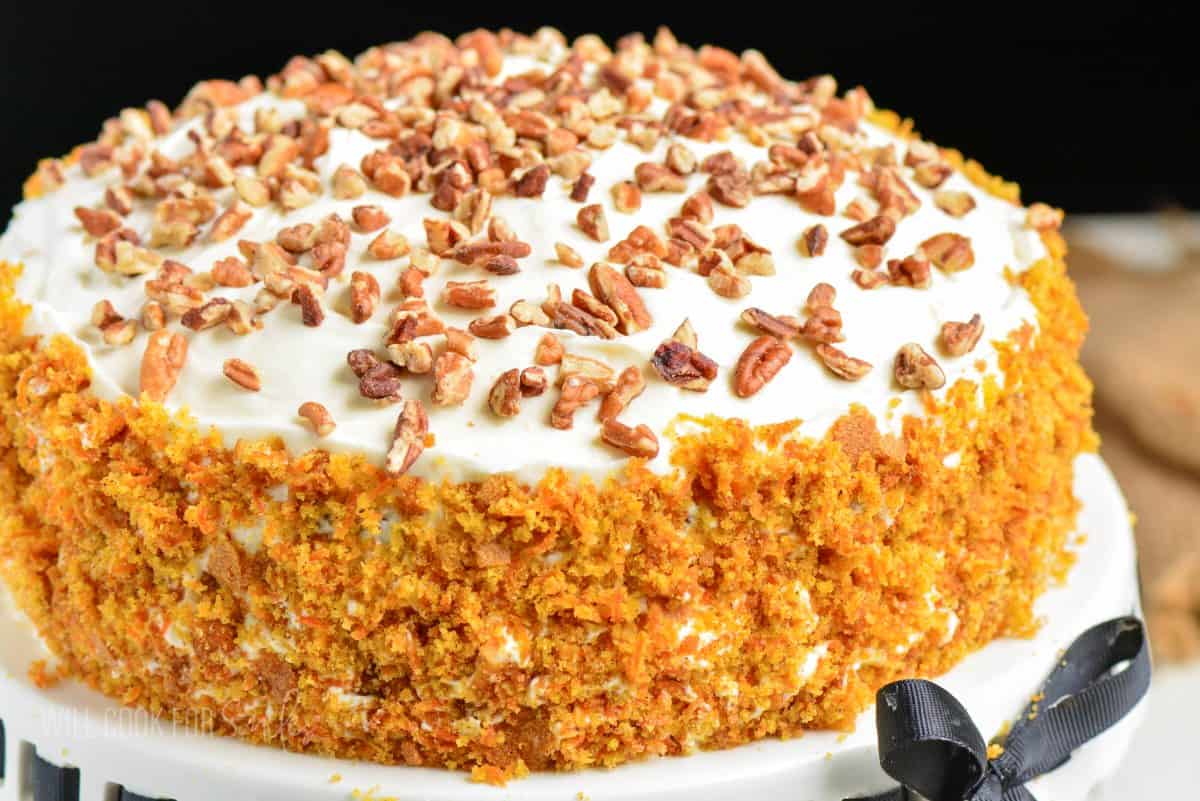 carrot cake decorated with chopped pecans and crumbled cake.