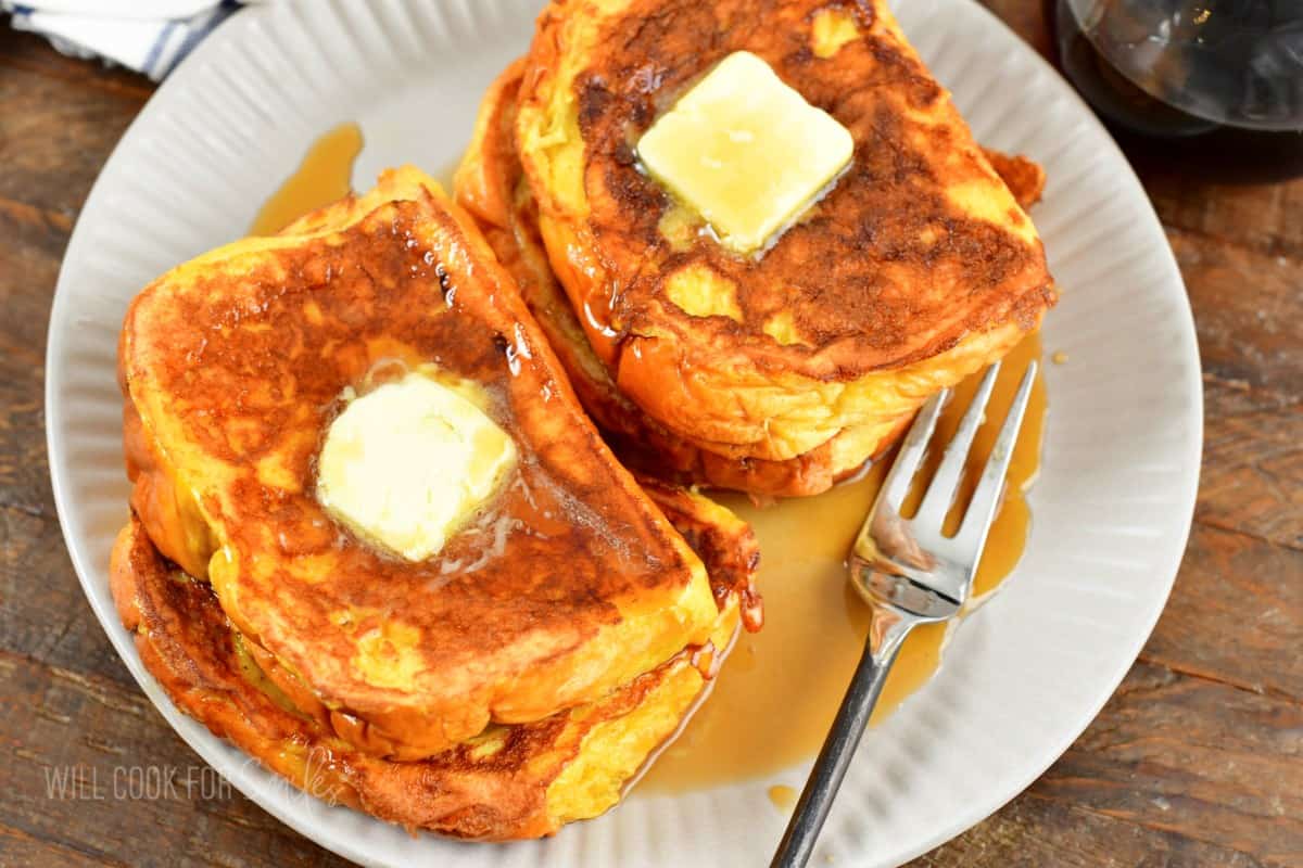 two small stacks of French toast topped with butter and maple syrup.
