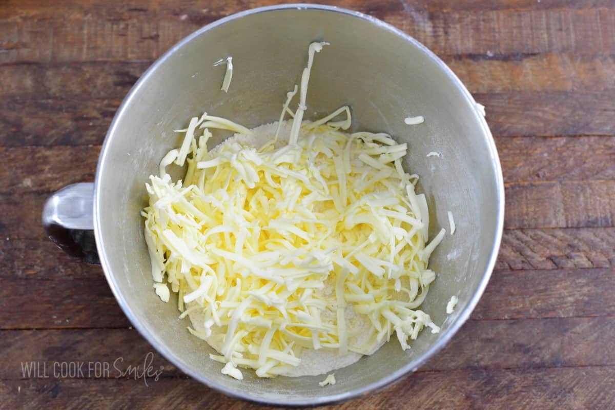 shaved butter added to the flour in a bowl.