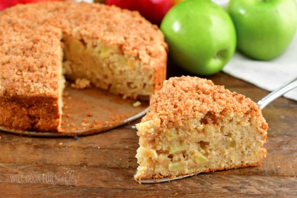 closeup of a slice of apple cake next to the whole.