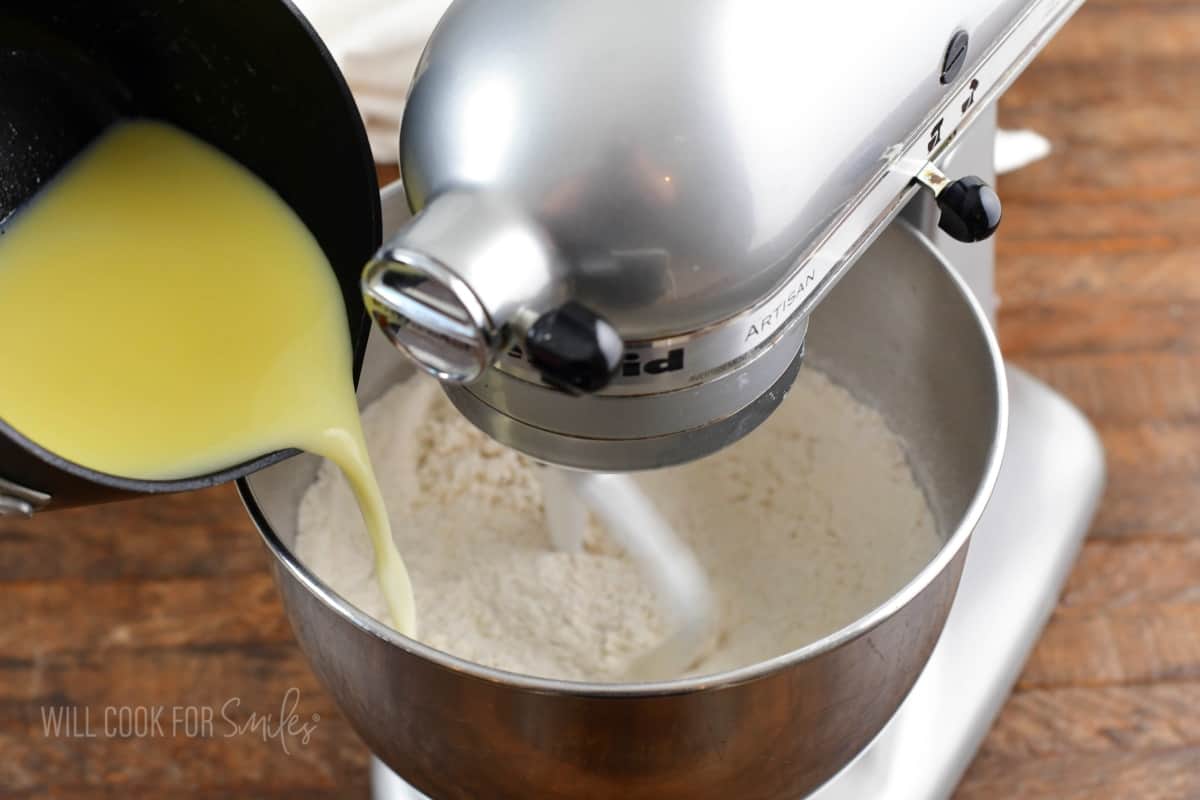 adding warmed milk and butter to the flour in mixing bowl.