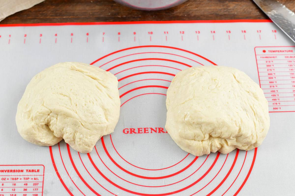 dinner roll dough split in two on the silicone mat.