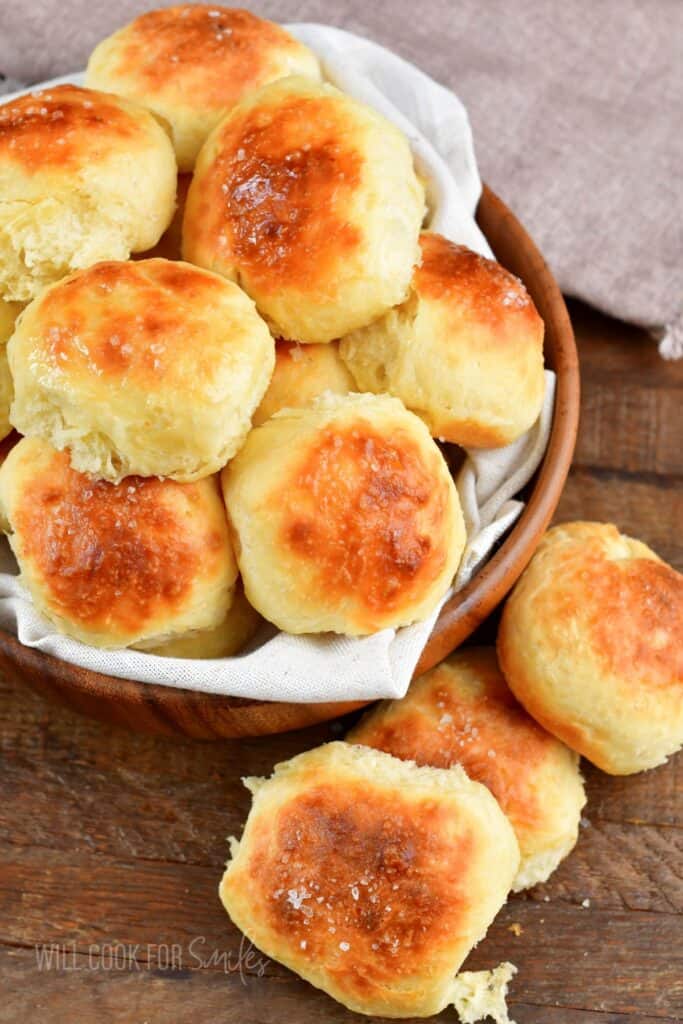 top view of several potato rolls in a bowl and some next to it.