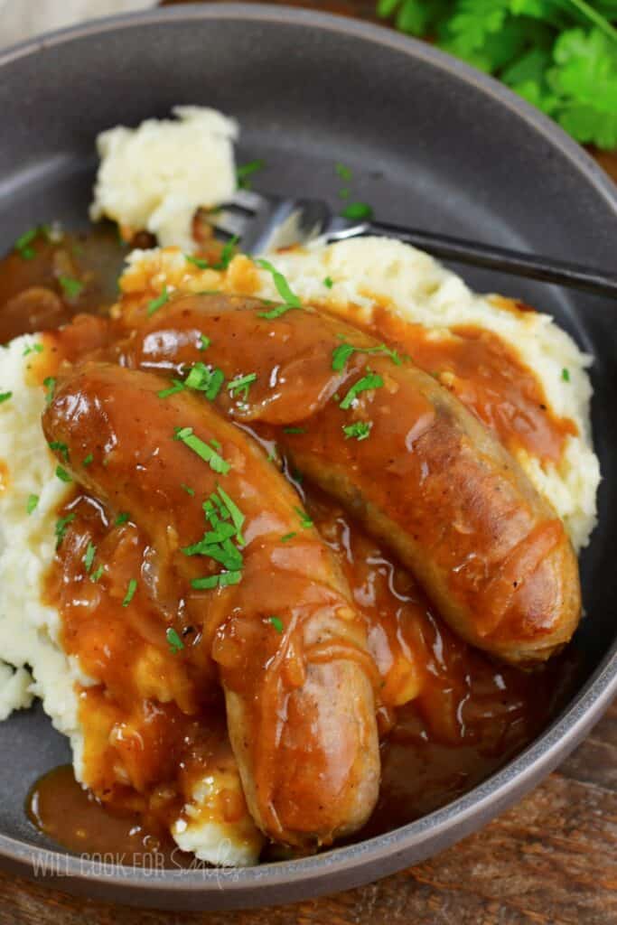 two sausages with gravy and mashed potatoes.