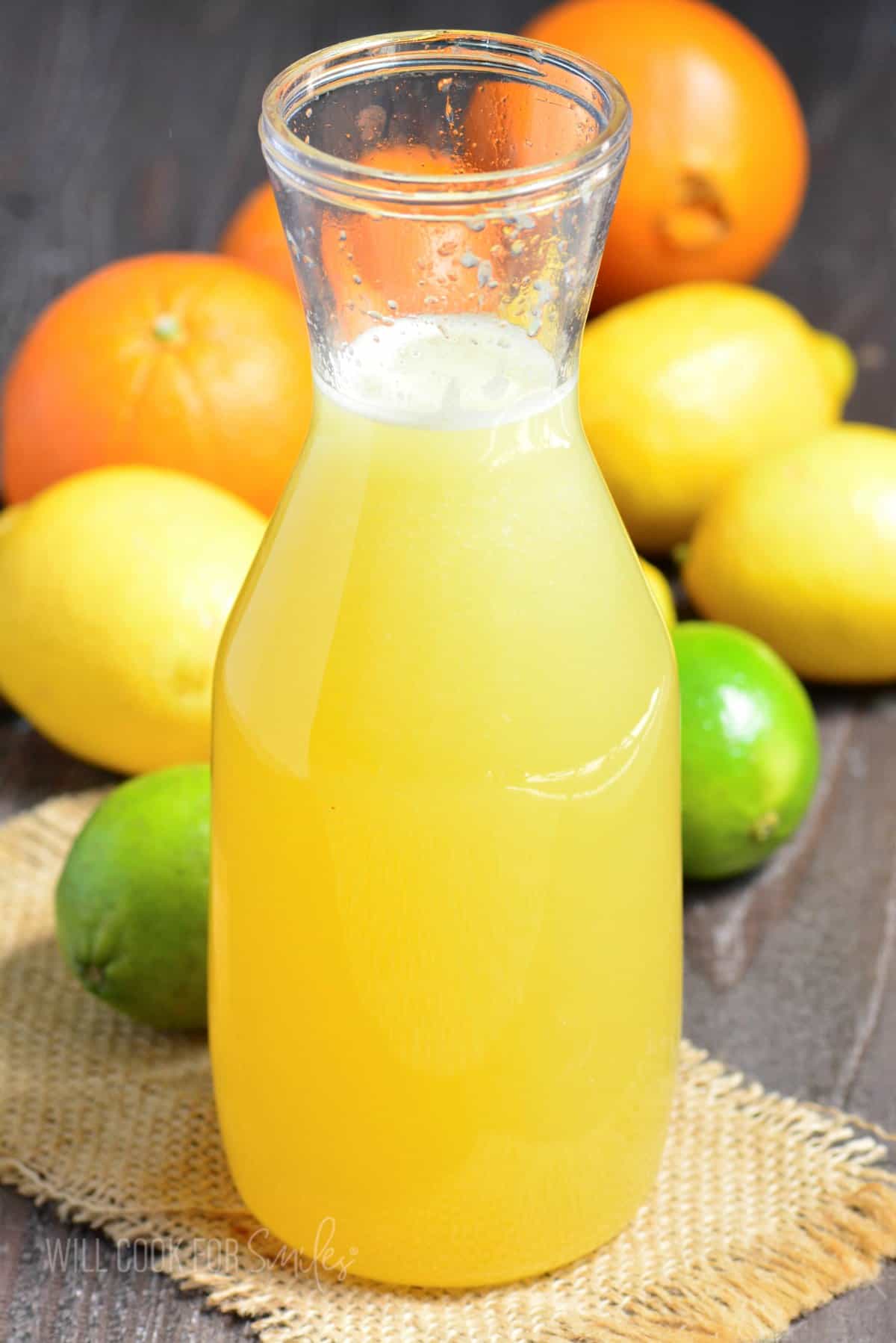 tall bottle filled with a bright margarita mix and citrus fruit around.
