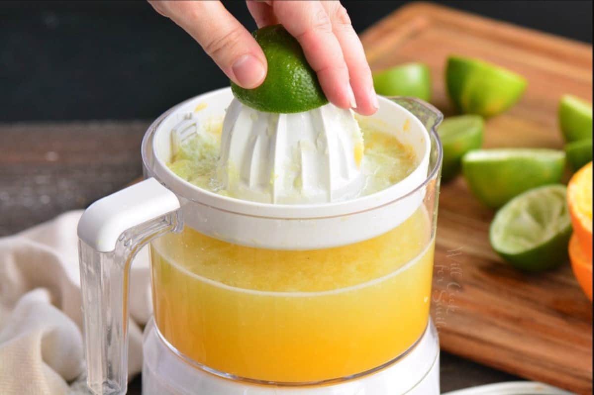 holding a lime half over the juicer to squeeze out the lime juice.