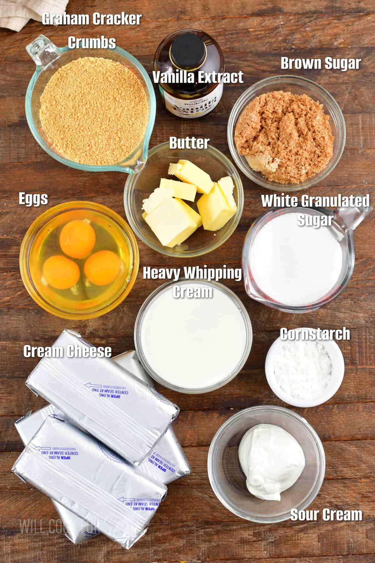 labeled ingredients for classic NY cheesecake on a wooden board.