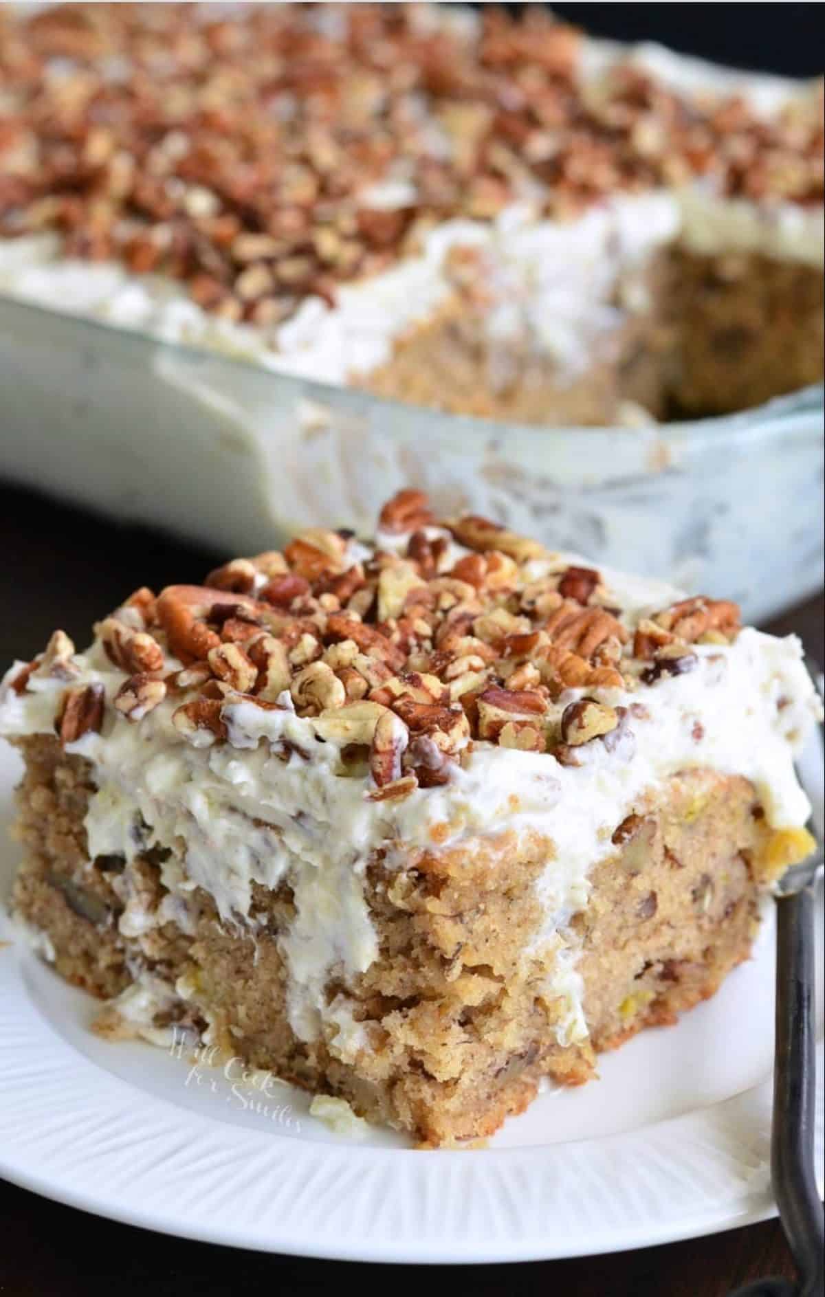 Square piece of hummingbird poke cake on a white plate next to the baking dish.