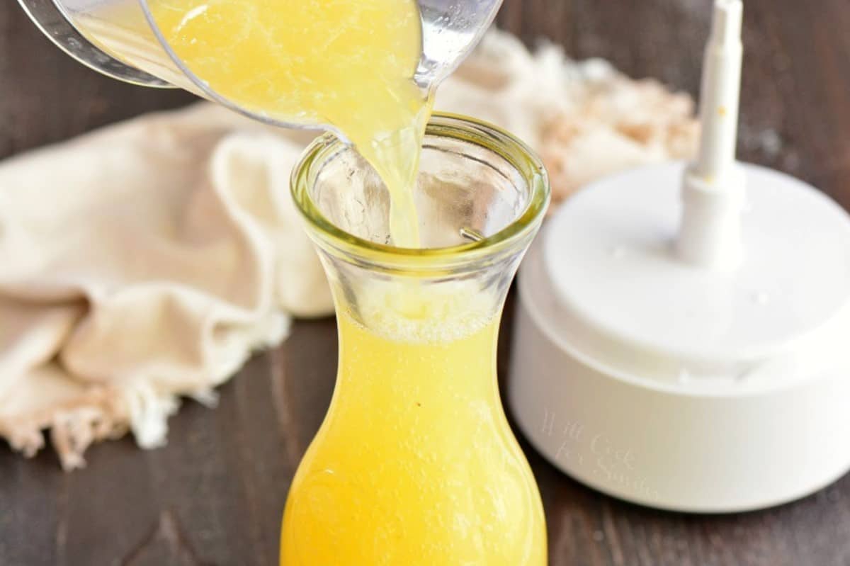 pouring margarita mix into a glass storage bottle.