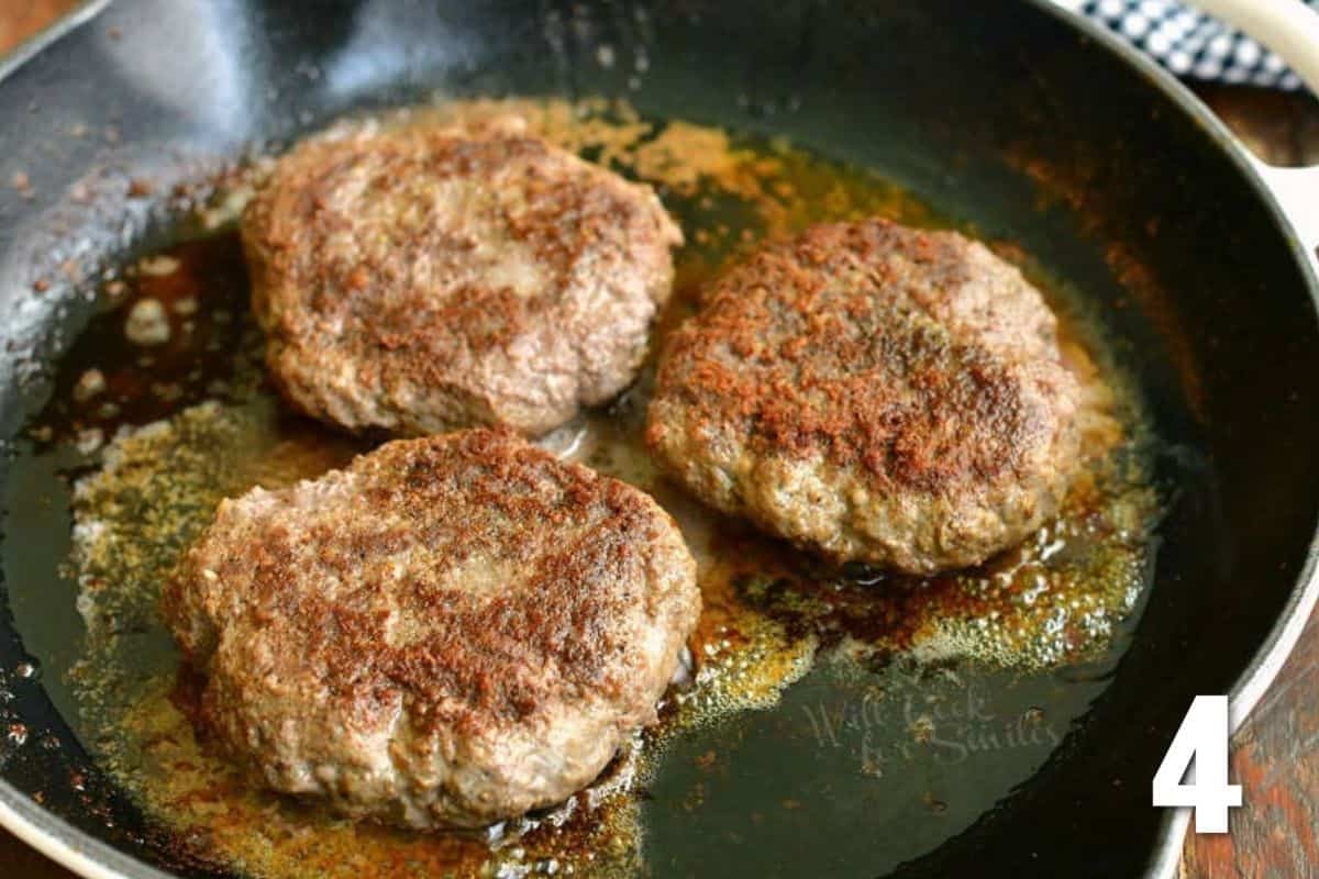 three burger patties cooking in the skillet.