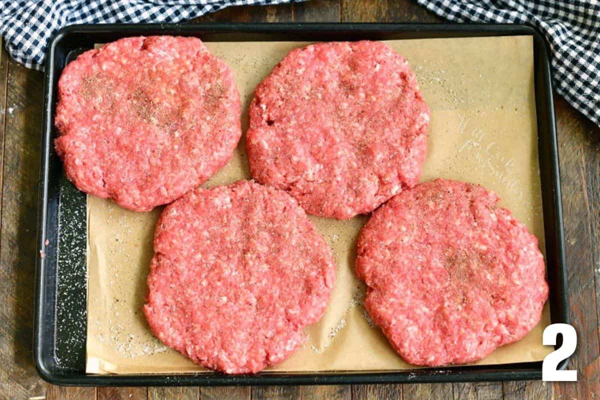 four burger patties shaped on parchment paper in a tray.