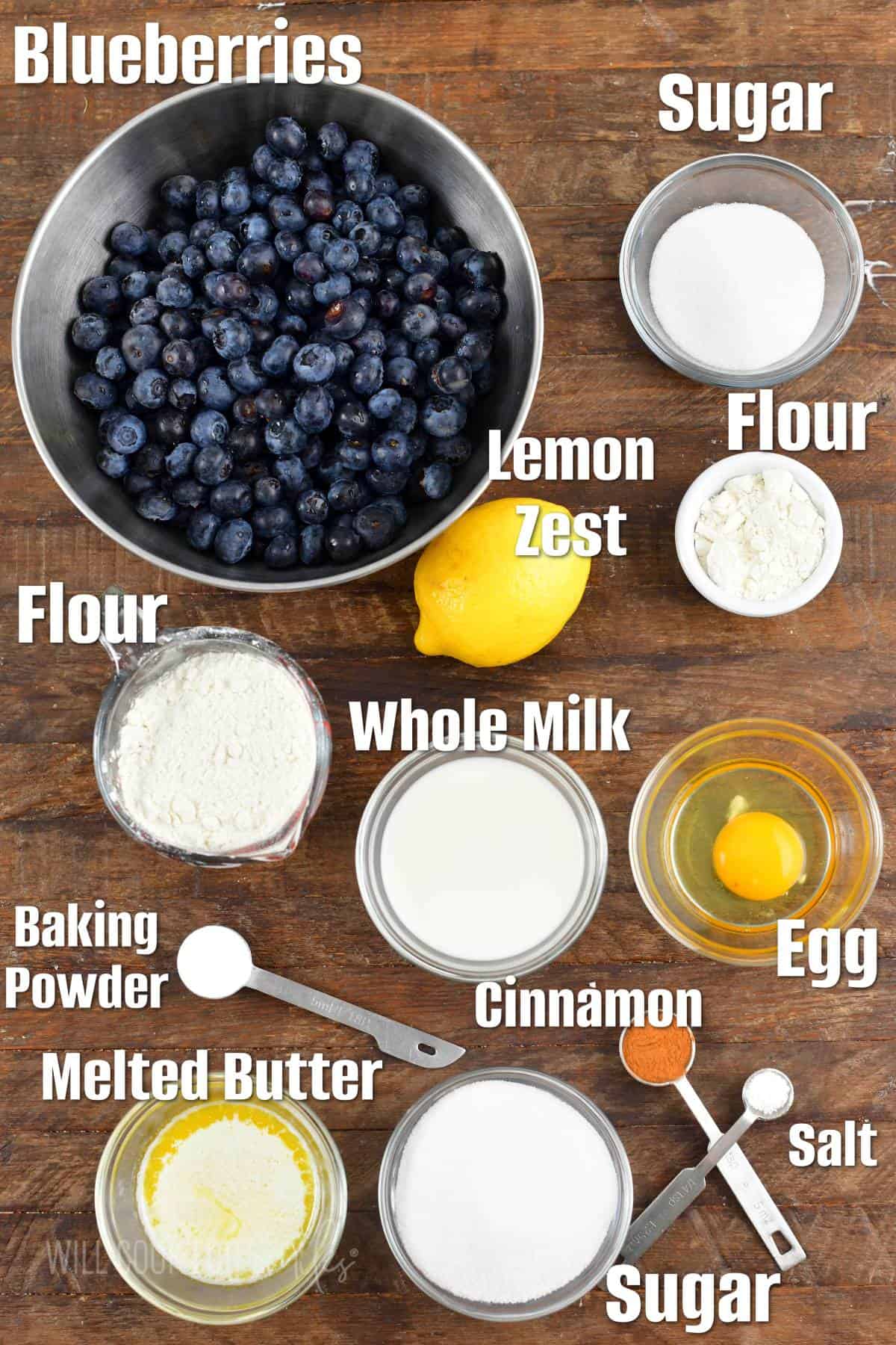 labeled ingredients to make blueberry cobbler on wooden board.