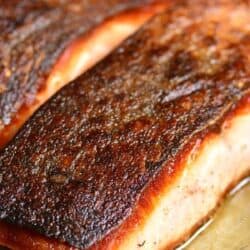 salmon filet in the pan with a brown crispy skin.